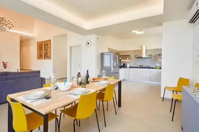 a dining room and kitchen with a wooden table and yellow chairs at Villa Etesiae in Castellammare del Golfo