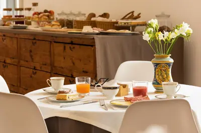 a table with a plate of food and a vase with flowers at Divisi Suites & SPA in Palermo
