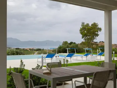 a patio with a table and chairs and a pool at Case Playa Resort in Balestrate