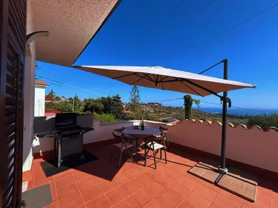 a patio with a table and a large umbrella at Casa Villea in Trabia