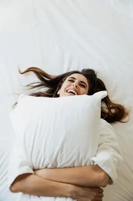 a woman laying in bed hugging a pillow at Domìa Boutique Hotel e Cucina in Mondello