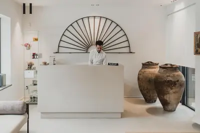 a man standing behind a counter in a room with vases at Domìa Boutique Hotel e Cucina in Mondello