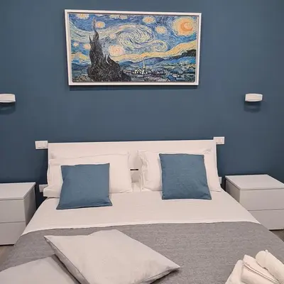 a bedroom with a large bed with a painting on the wall at La Casa Di Amalia in Palermo