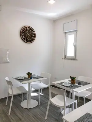 a dining room with white tables and chairs and a clock at La Casa Di Amalia in Palermo