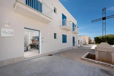 a white building with a balcony and a courtyard at Scrusciu du mari in San Vito lo Capo