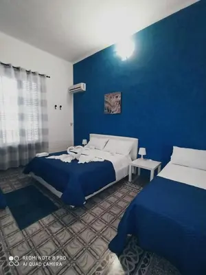 a bedroom with two beds and a blue wall at Stanze Di Leo in Palermo