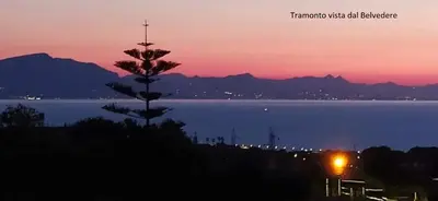 a sunset over the water with a tree in the foreground at B&B Rainbow in Campofelice di Roccella