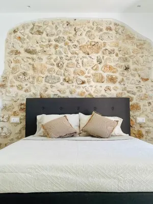 a bedroom with a stone wall and a large bed at Curina Luxury Villa - Panoramic Pool Villa near Scopello in Castellammare del Golfo