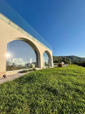 a building with a large window on top of a grass field at Curina Luxury Villa - Panoramic Pool Villa near Scopello in Castellammare del Golfo