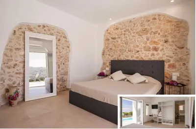 a bedroom with a bed and a stone wall at Curina Luxury Villa - Panoramic Pool Villa near Scopello in Castellammare del Golfo