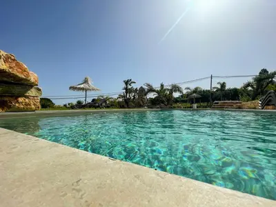 a swimming pool with blue water in a resort at Splendida Villa NATURE-APPARTAMENTO MELOGRANO a SCOPELLO-ZINGARO vista sul mare in Scopello