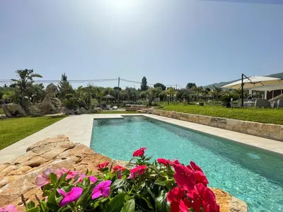 a swimming pool with pink flowers in a yard at Splendida Villa NATURE- APPARTAMENTO ARANCIO a Scopello - Zingaro in Scopello