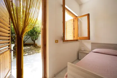 a bedroom with a window and a bed and a mirror at APPARTAMENTI BLUSANVITO P-TERRA in San Vito lo Capo