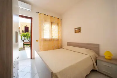 a bedroom with a bed and a yellow curtain at APPARTAMENTI BLUSANVITO P-TERRA in San Vito lo Capo