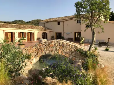 a stone bridge over a pond in front of a house at Agriturismo Antichi Granai in Calatafimi