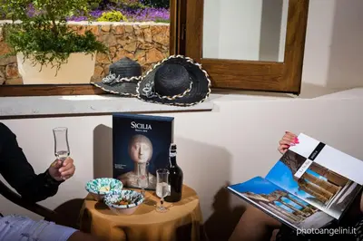 a table with a bottle of wine and a person holding a glass at Agriturismo Antichi Granai in Calatafimi