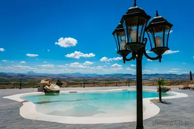 a woman sitting next to a light pole next to a pool at Agriturismo Antichi Granai in Calatafimi