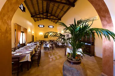 a dining room with tables and a plant in a pot at Agriturismo Antichi Granai in Calatafimi