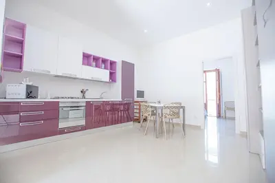 a kitchen with purple cabinets and a table with chairs at Casa in centro in Castellammare del Golfo