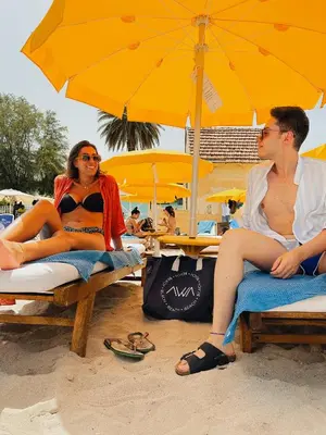 two people sitting on the beach under an umbrella at AWA Mondello in Mondello
