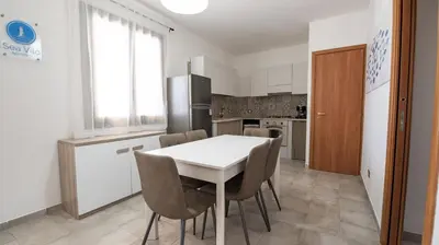 a kitchen with a table and chairs and a refrigerator at Sea Vito Apartment in San Vito lo Capo