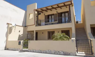 a house with a gate and a balcony at Sea Vito Apartment in San Vito lo Capo