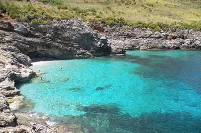 a large pool of blue water next to a beach at Casa vacanza Corallo in Castellammare del Golfo