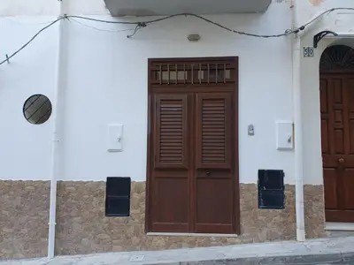a building with two wooden doors on the side at Casa vacanza Corallo in Castellammare del Golfo