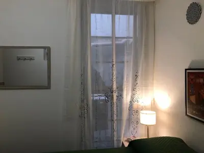 a window with white curtains and a green couch at Casa di fronte la Cattedrale in Palermo