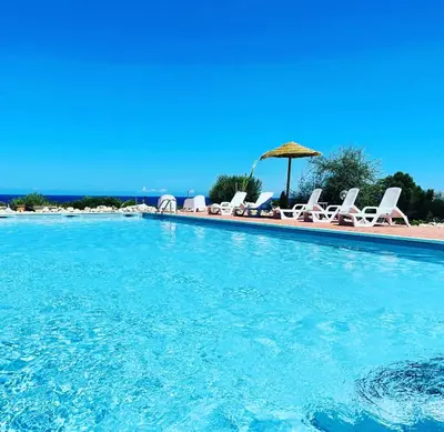 a swimming pool with chairs and an umbrella at Villa dell’Orsa in Cinisi