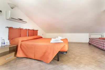 a bedroom with an orange bed with towels on it at Case Vacanze Paradise Beach Vicino Cefalù PISCINA APERTA in Campofelice di Roccella