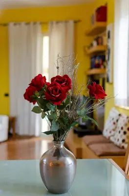 a vase filled with red roses on a table at POLICLINICO HOME in Palermo