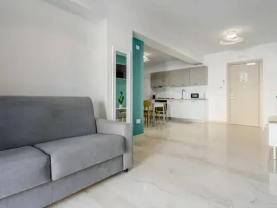 a living room with a couch and a kitchen at Azzurra Apartments in Balestrate