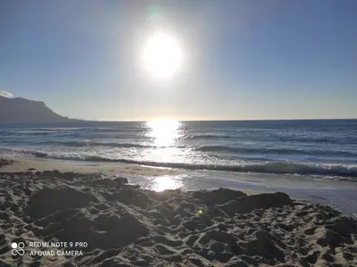 a beach with the sun rising over the ocean at La casa di Giulio - holiday home in Isola delle Femmine
