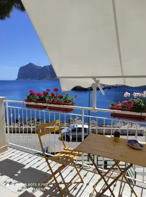 a chair and a table on a balcony with the ocean at La casa di Giulio - holiday home in Isola delle Femmine