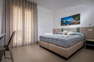 a bedroom with a bed and a table and a desk at Affittacamere Nanà in Castellammare del Golfo