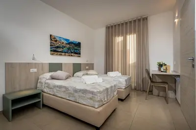 a hotel room with two beds and a desk at Affittacamere Nanà in Castellammare del Golfo