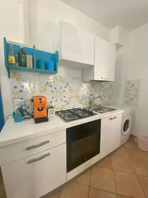 a kitchen with white cabinets and a stove top oven at Cartari Apartment in Palermo