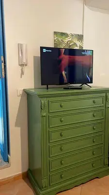 a green dresser with a television on top of it at Cartari Apartment in Palermo