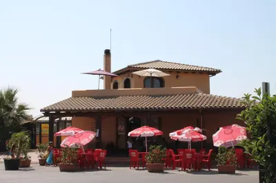 a restaurant with red chairs and red umbrellas at Campofelice Holidays in Campofelice di Roccella