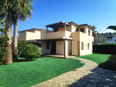 a house with a green lawn in front of it at Campofelice Holidays in Campofelice di Roccella