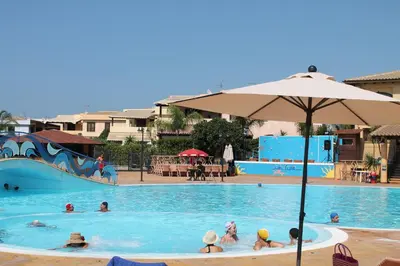 people in a swimming pool with an umbrella at Campofelice Holidays in Campofelice di Roccella