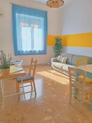 a living room with a couch and a table and chairs at Vento di Grecale - a pochi metri dal mare in Santa Flavia