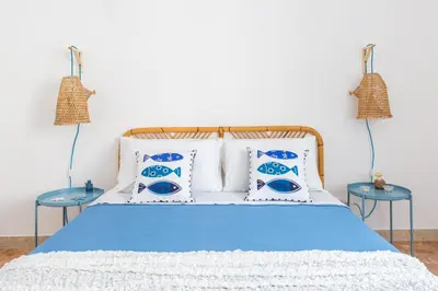 a bed with blue and white pillows and two tables at Vento di Grecale - a pochi metri dal mare in Santa Flavia