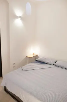 a white bedroom with a bed and a night stand at Mediterranea - Piccola Dimora per Viaggiatori in Castellammare del Golfo