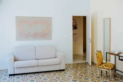 a living room with a white couch and a chair at Calamarina Centro in Palermo