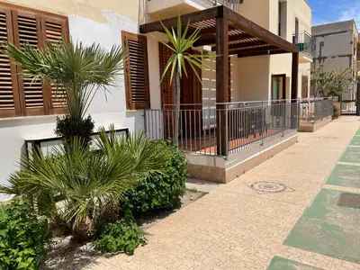a house with a balcony with palm trees in front of it at Casa Vacanze Costanza in San Vito lo Capo