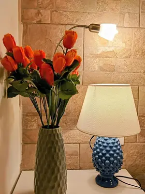 a vase with orange flowers sitting on a table next to a lamp at Zisa Home ai Cantieri Culturali con Patio Privato - vicino centro storico - No ZTL in Palermo