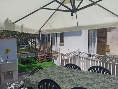 a table and chairs under a white umbrella on a balcony at A casa di nonna Maria in Terrasini
