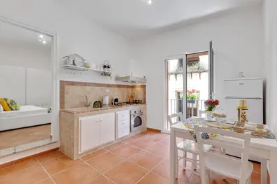 a kitchen with white cabinets and a table with chairs at GuestHost - Vucciria Market Apartment with Balconies in Palermo